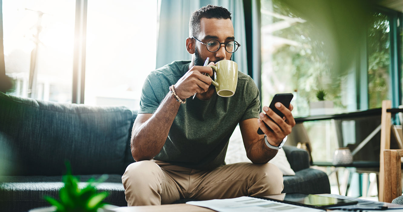 Man on phone drinking coffee at home