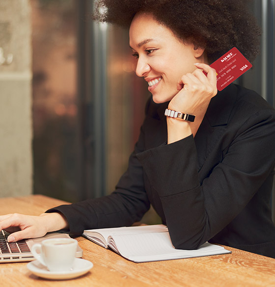 Woman using a Kalsee credit card while on a computer at a coffee shop
