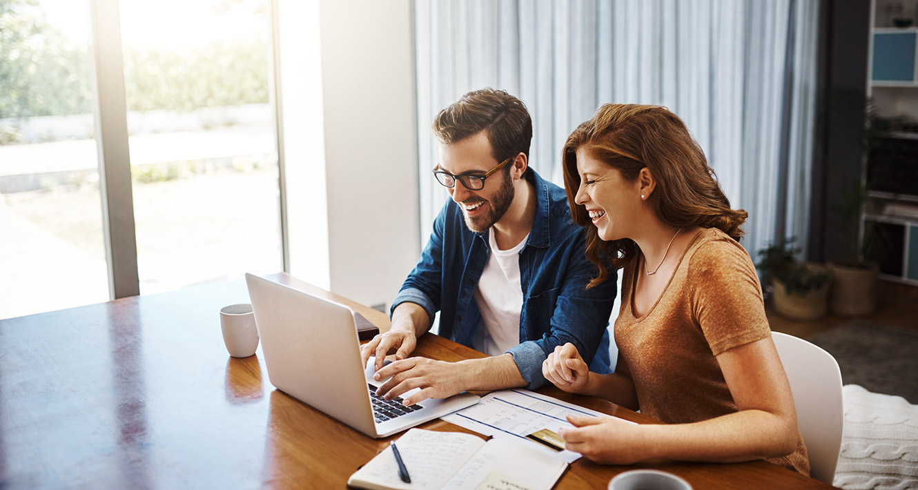 Young couple using computer at kitchen table