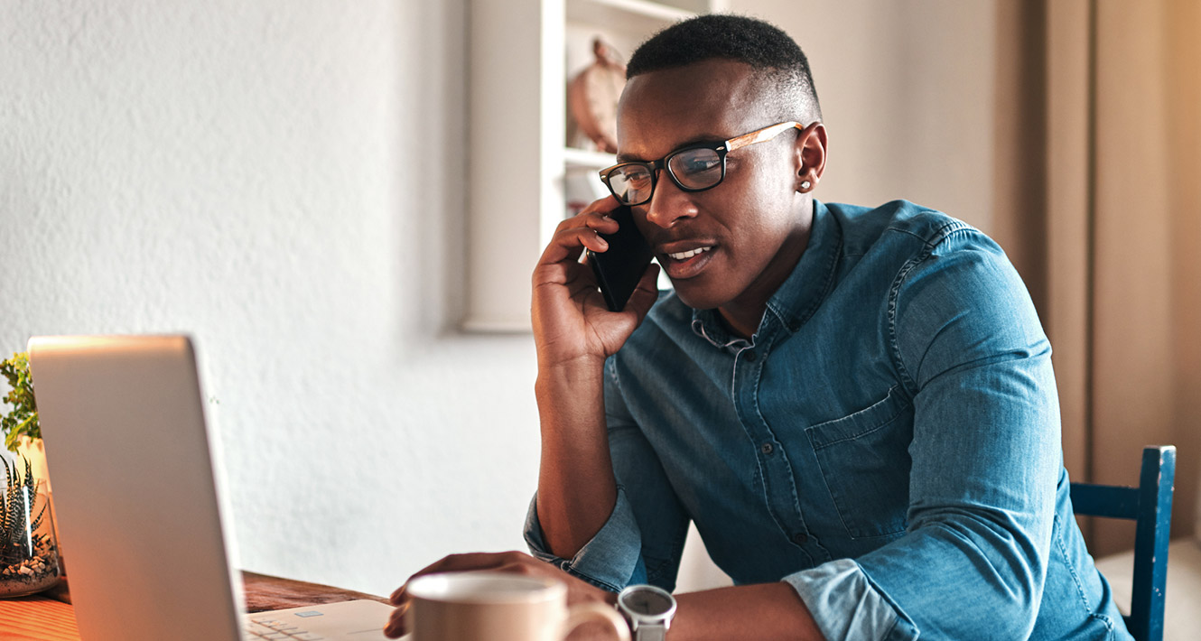 Man talking on phone in front of computer